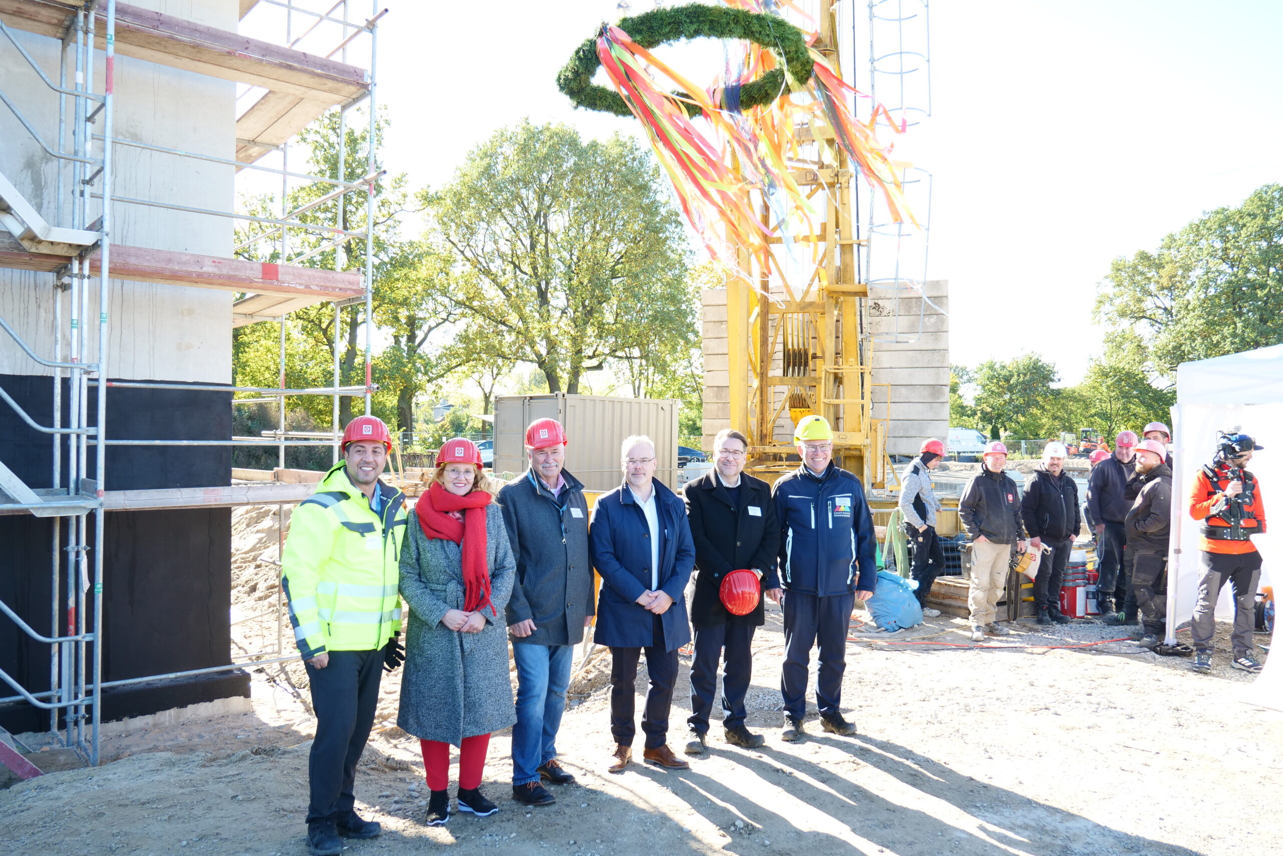 Projektbeteiligete stehen in einer Reihe unter dem Richtkranz.